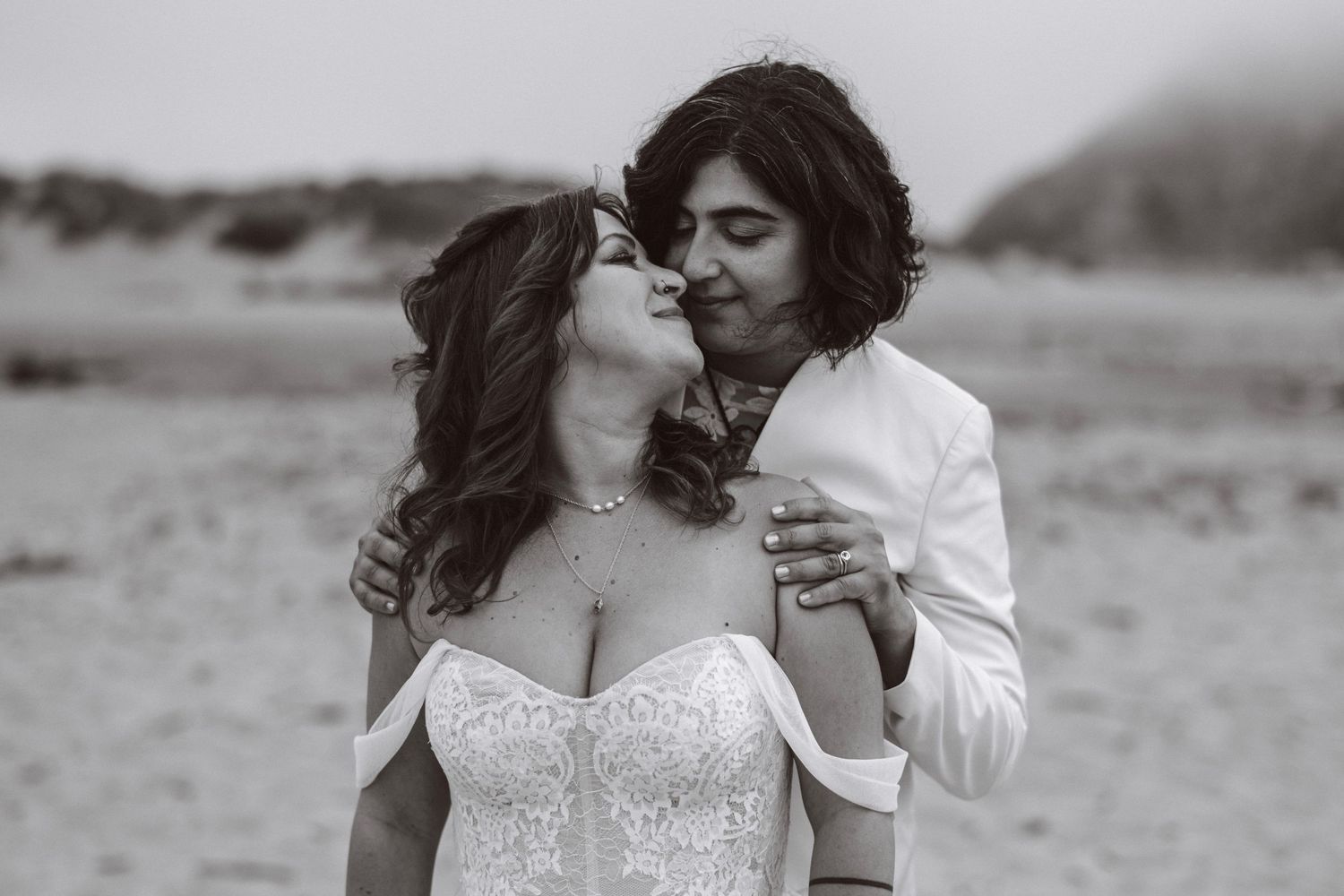 Black and white photo of bride and groom sharing a tender kiss in an open field.