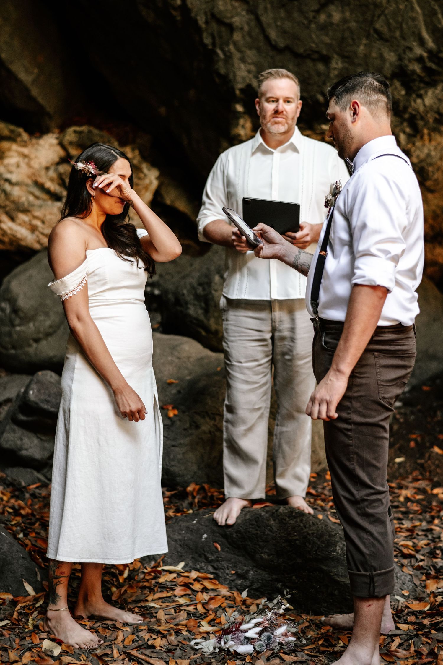 Emotional bride and groom exchanging vows during an intimate beach cave elopement.