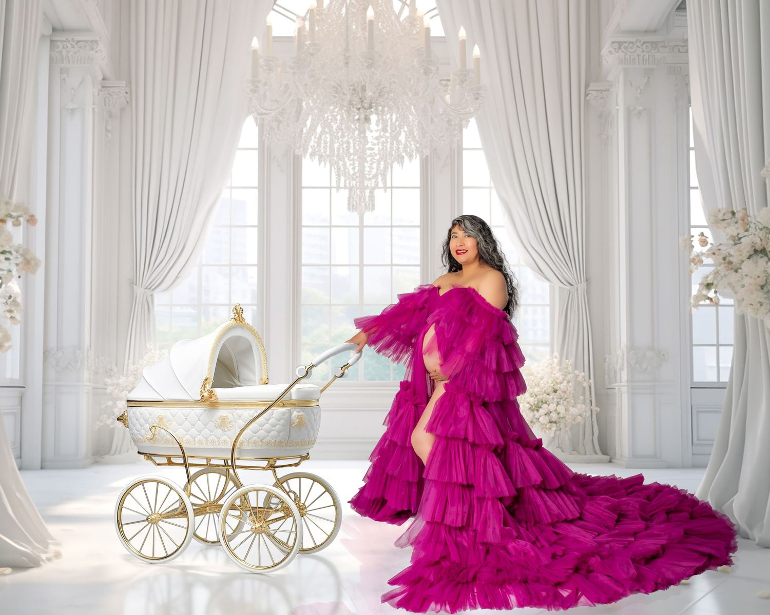 Woman in luxurious fuchsia tulle gown poses with vintage baby carriage in elegant white room with crystal chandelier.