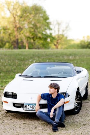 A white vintage sports car photographed from multiple angles on grassy terrain during a sunset photoshoot.