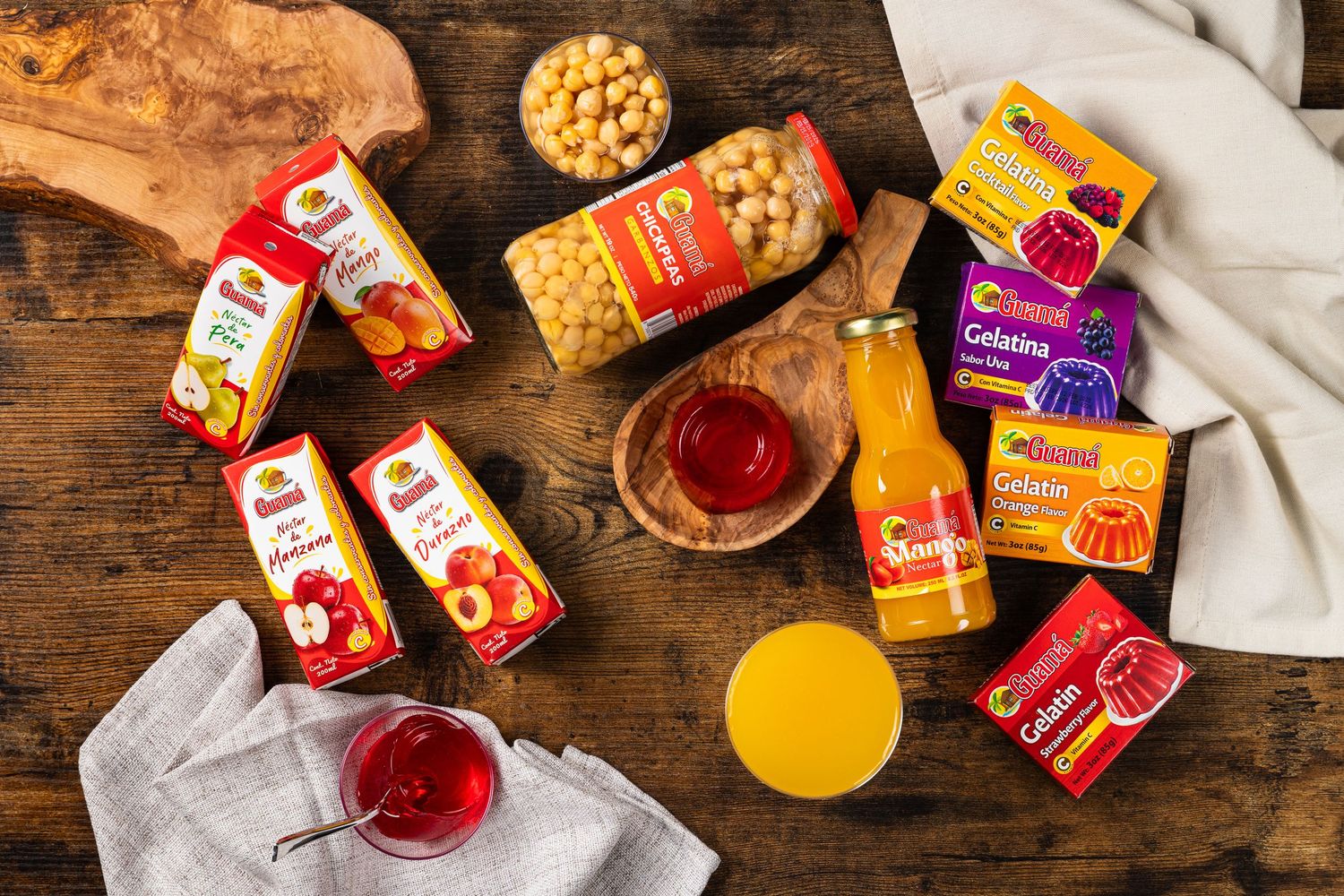 Assorted fruit juices, canned chickpeas, and gelatin products displayed on a rustic wooden table.