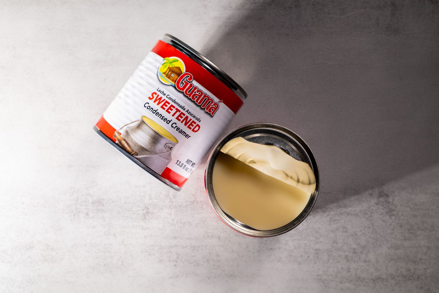 A jar of Jif creamy peanut butter with a spoonful of smooth peanut butter next to it on a gray surface.