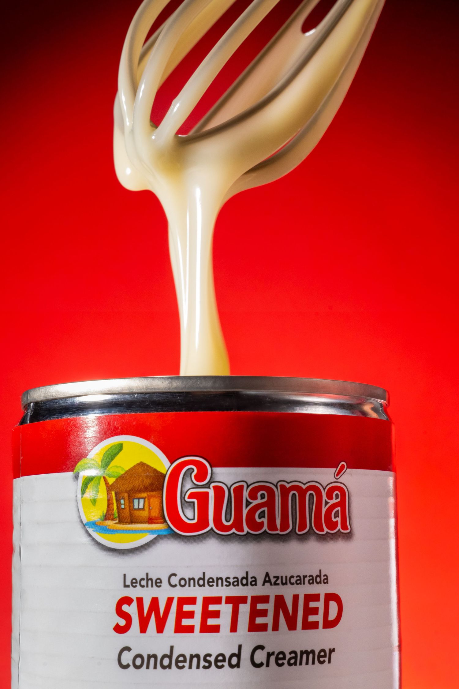 White creamy liquid pours artistically against a vibrant red background in a commercial food photography setup.