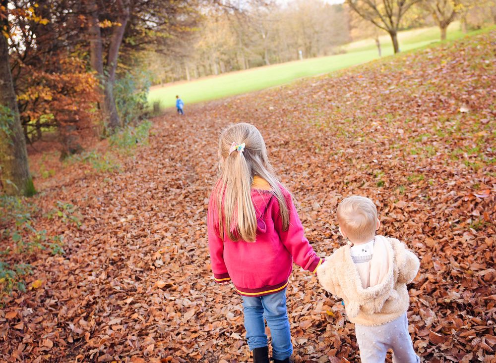 Sister holding her little brothers hand on their family walk at Balbirnie.