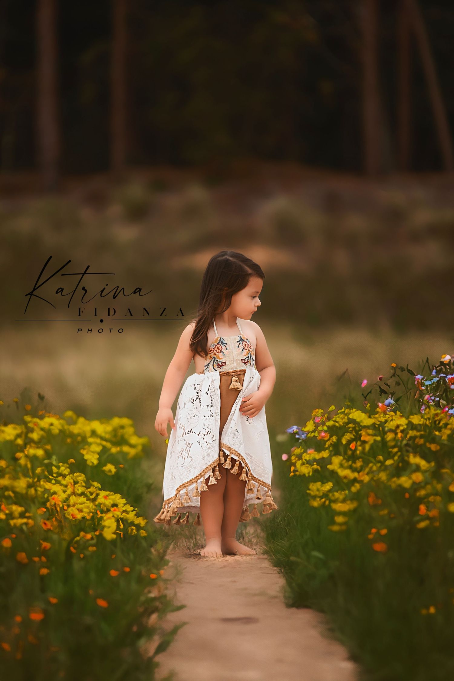 Young girl in white dress walks along path through field of yellow wildflowers.
