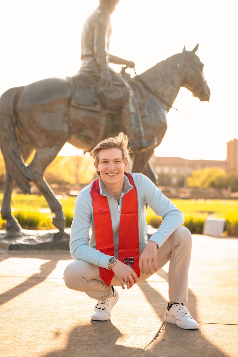 A casual portrait in front of a horse statue during golden hour.