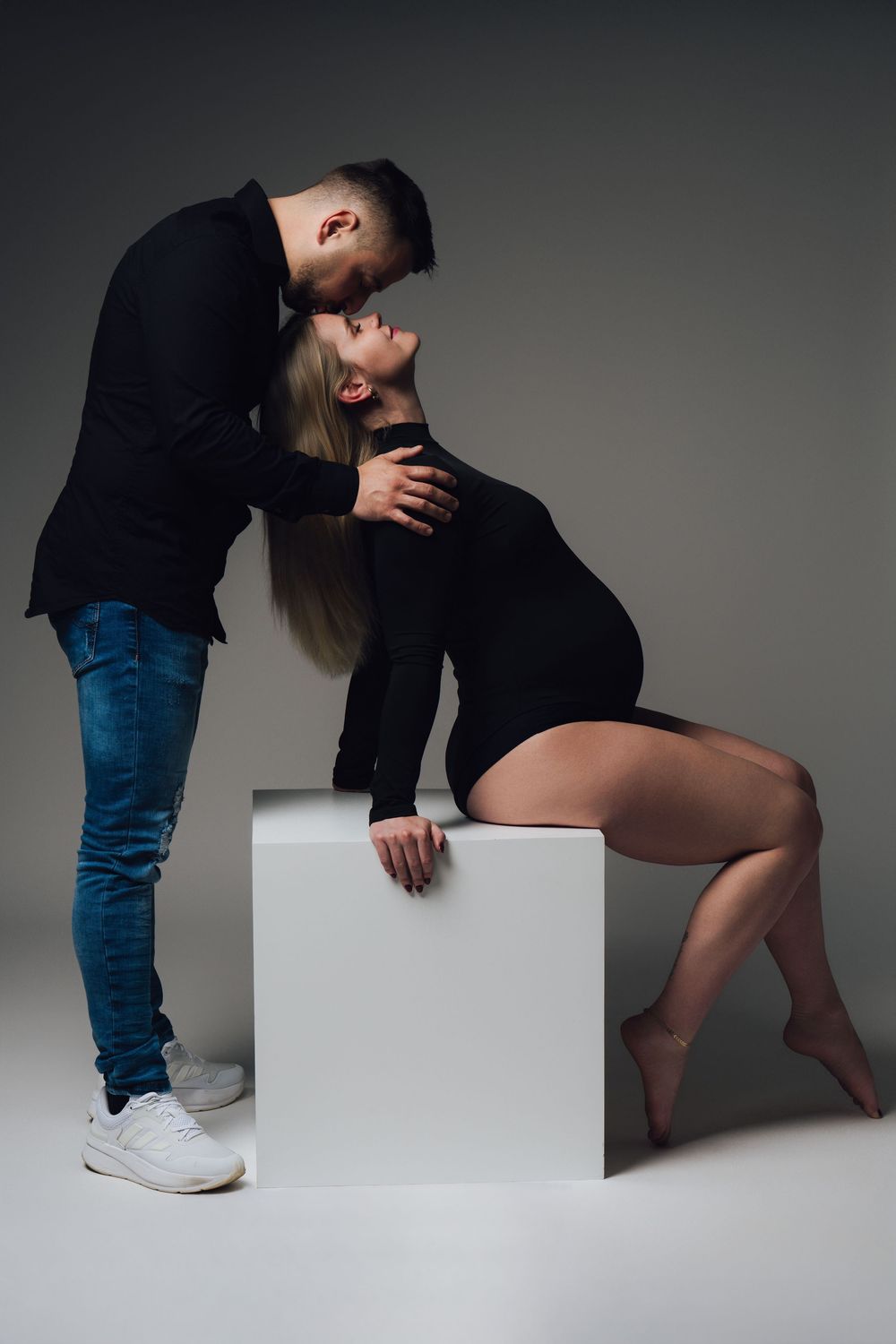 Artistic fashion shoot with models posing on white geometric blocks.