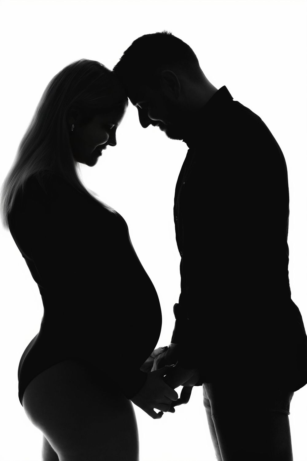 Silhouette of expectant couple holding hands in intimate pose against white background.