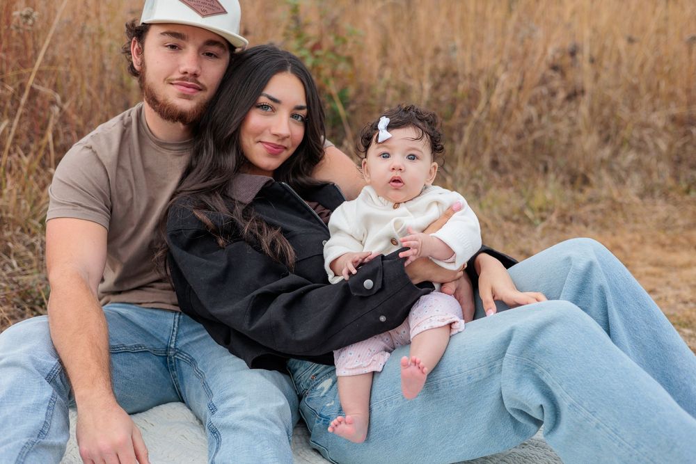 Family lying together on blanket in field during outdoor portrait session.