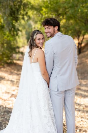 Bride and groom looking back at the camera during couple portraits with trees behind them at Orland, California Wedding