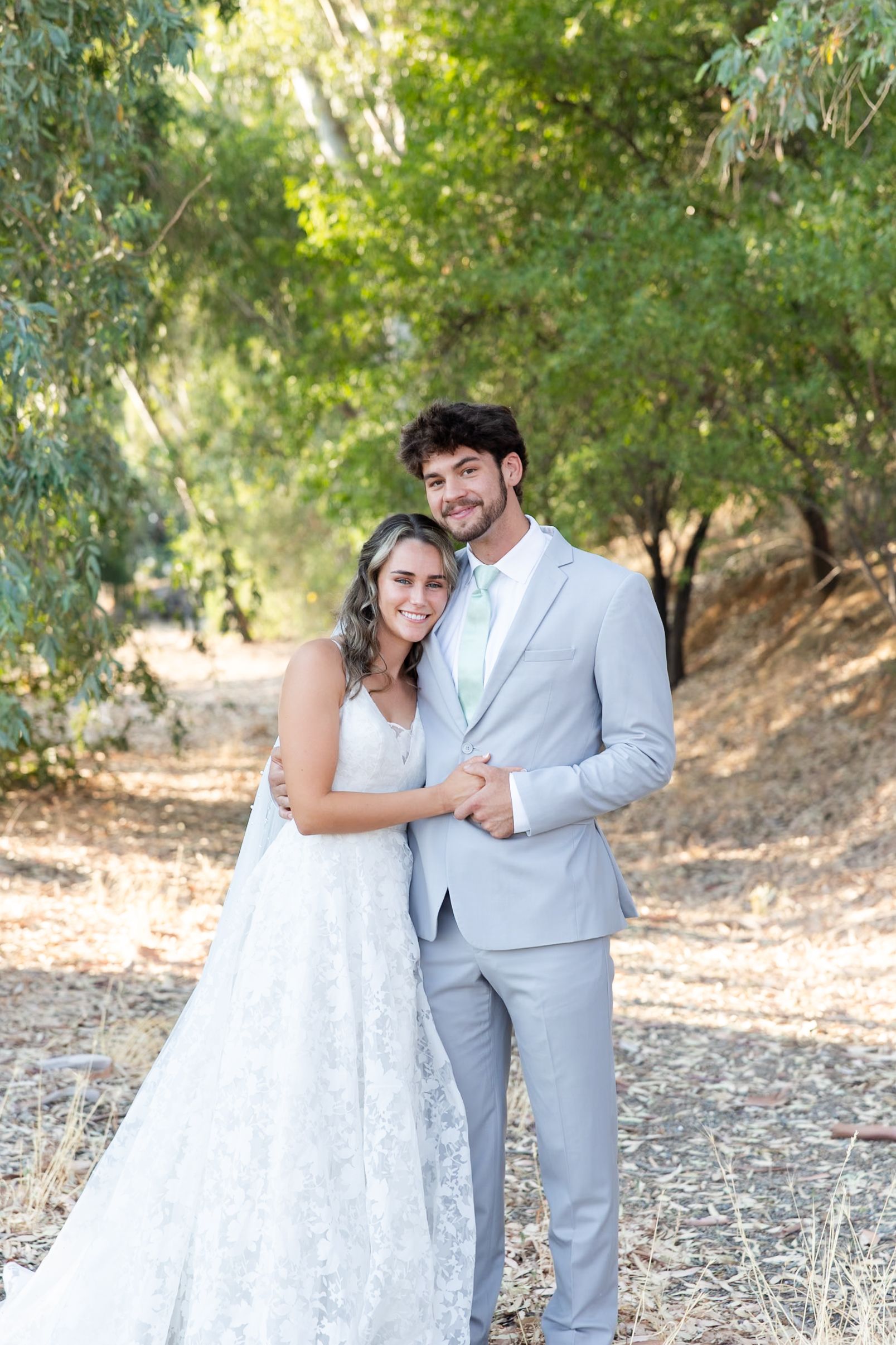 Bride and groom during couple portraits with green trees behind them at Orland, California Wedding