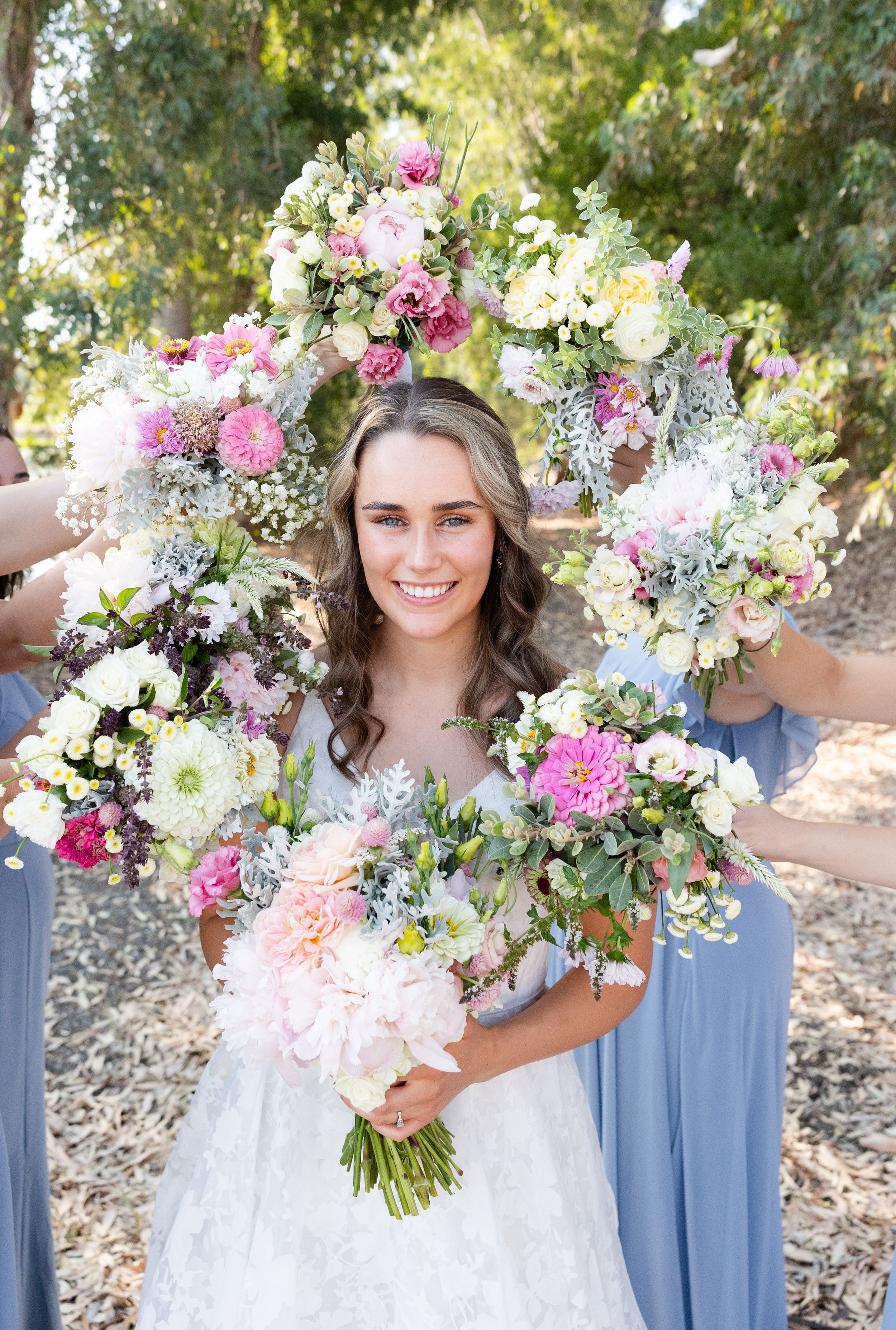 Bride smiling at camera surrounded by bouquets in Orland, California Wedding