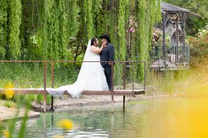 Bride and groom share a romantic kiss on a garden bridge over a pond, surrounded by weeping willows. White Ranch Wedding, Chico California
