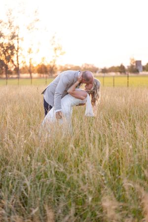 Bride and groom kissing in golden field with trees in the background at Orland, California Wedding