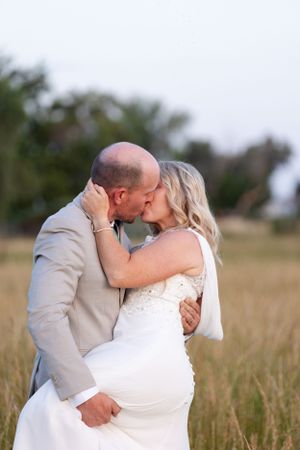 Bride and groom kissing in golden field with trees in the background at Orland, California Wedding