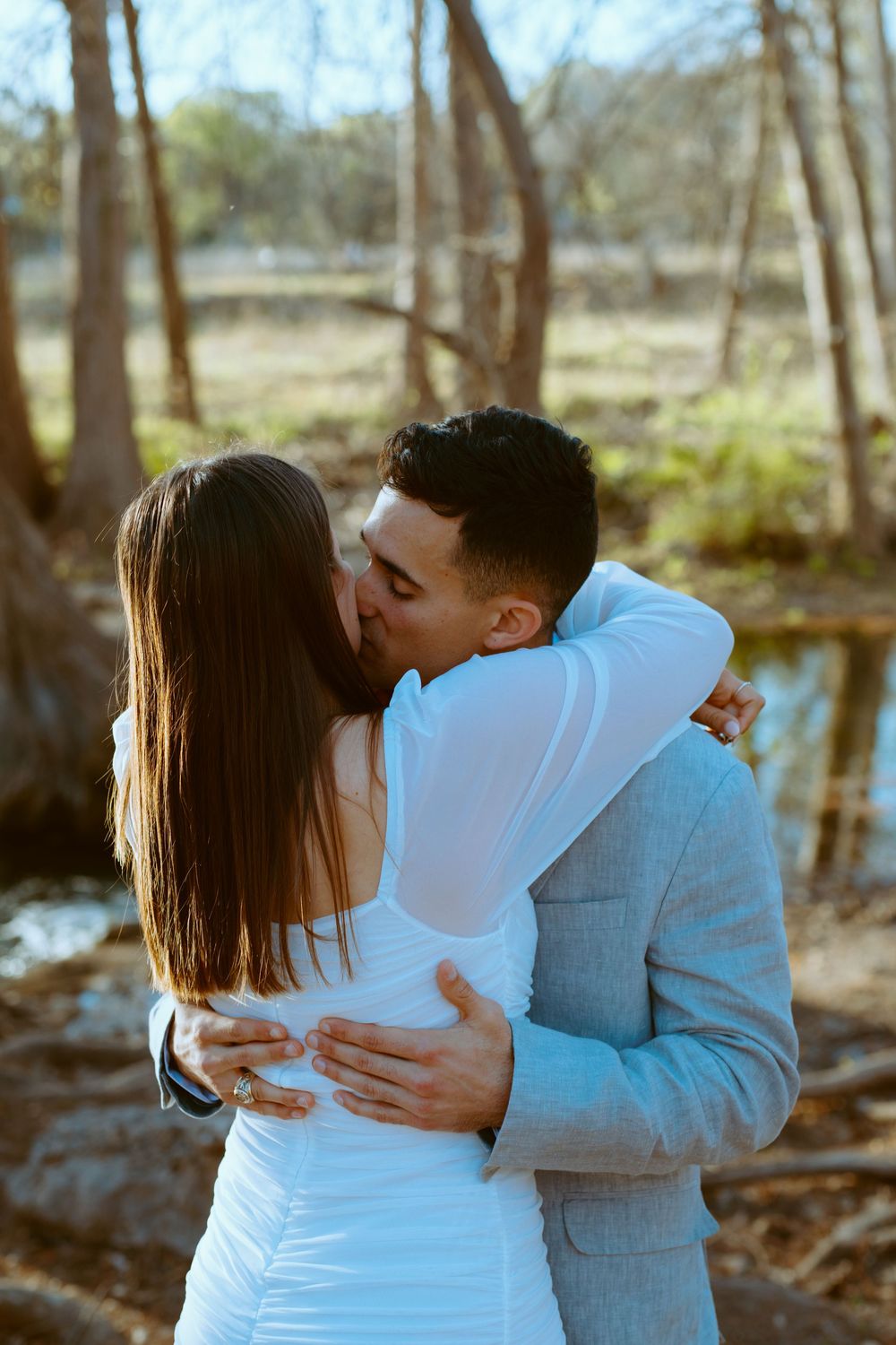 engagement photography session featuring a couple kissing outdoors surrounded by scenic trees and nature at Wimberley cabins on the square