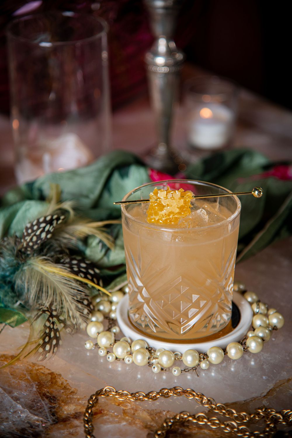 Elegant cocktails garnished with gold flakes and pearls on a textured surface with decorative lighting.