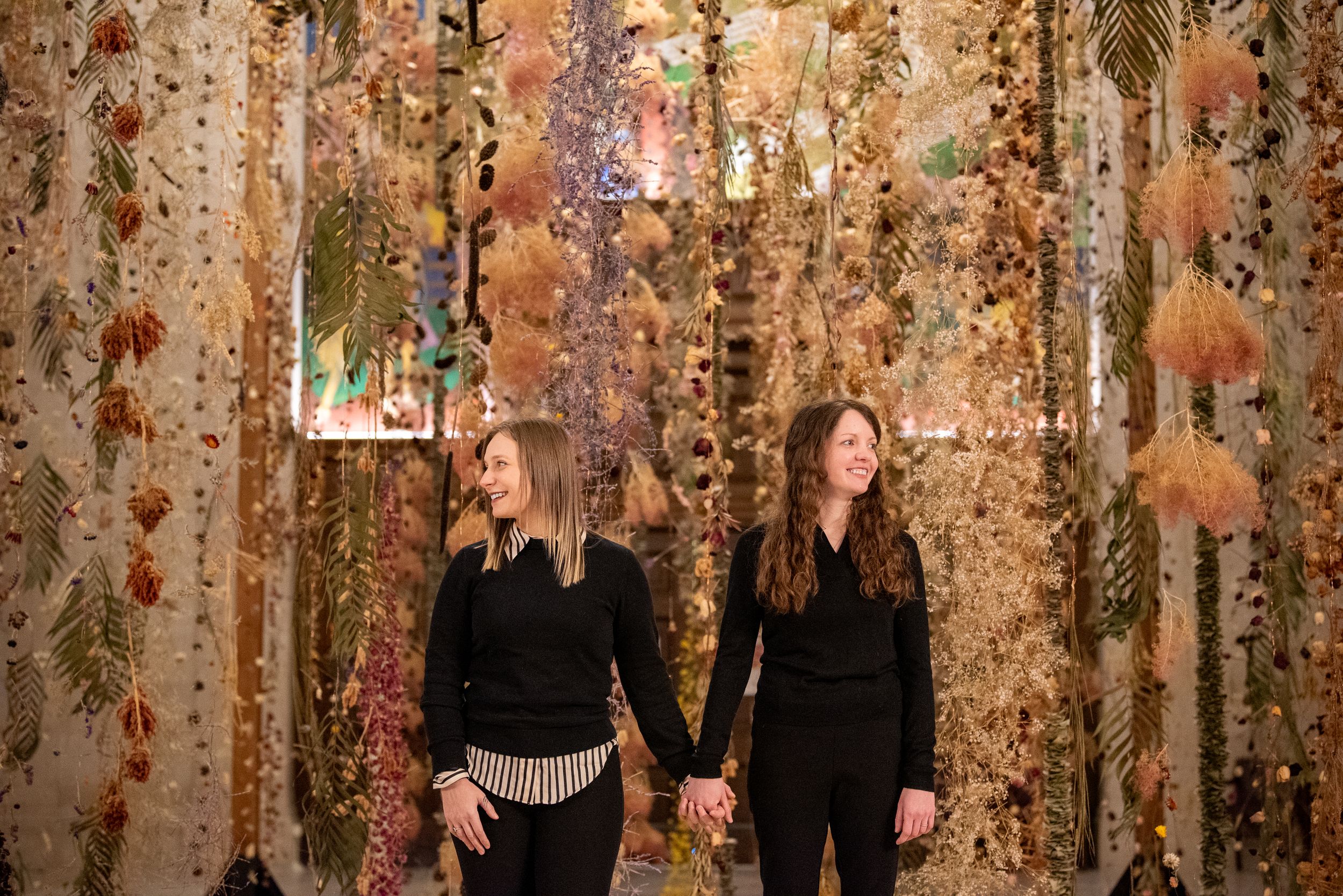 Autumn-themed wedding ceremony backdrop with hanging floral arrangements and warm lighting creates a romantic atmosphere.
