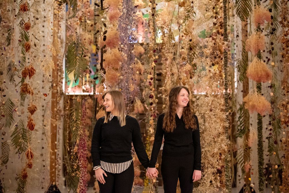 Autumn-themed wedding ceremony backdrop with hanging floral arrangements and warm lighting creates a romantic atmosphere.