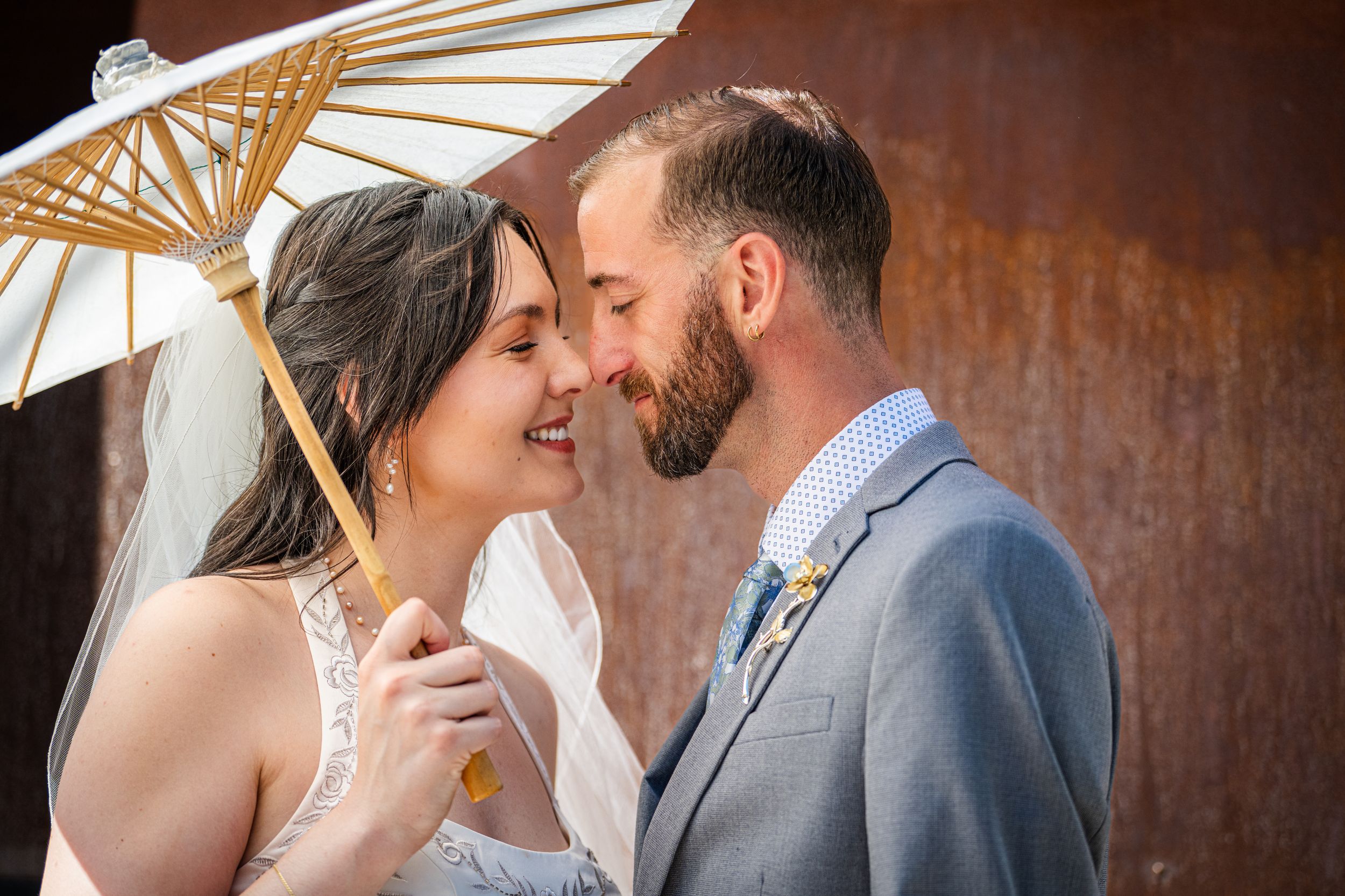 Romantic wedding couple embracing under rustic metal architectural detail.