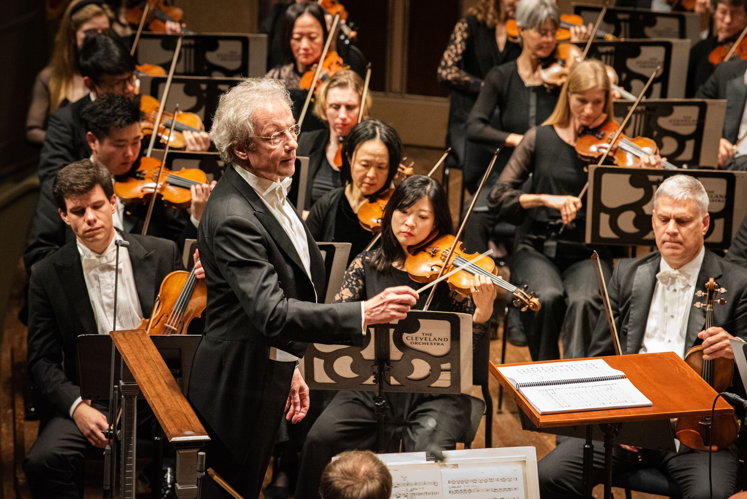Symphony orchestra musicians perform with their instruments during a classical concert.