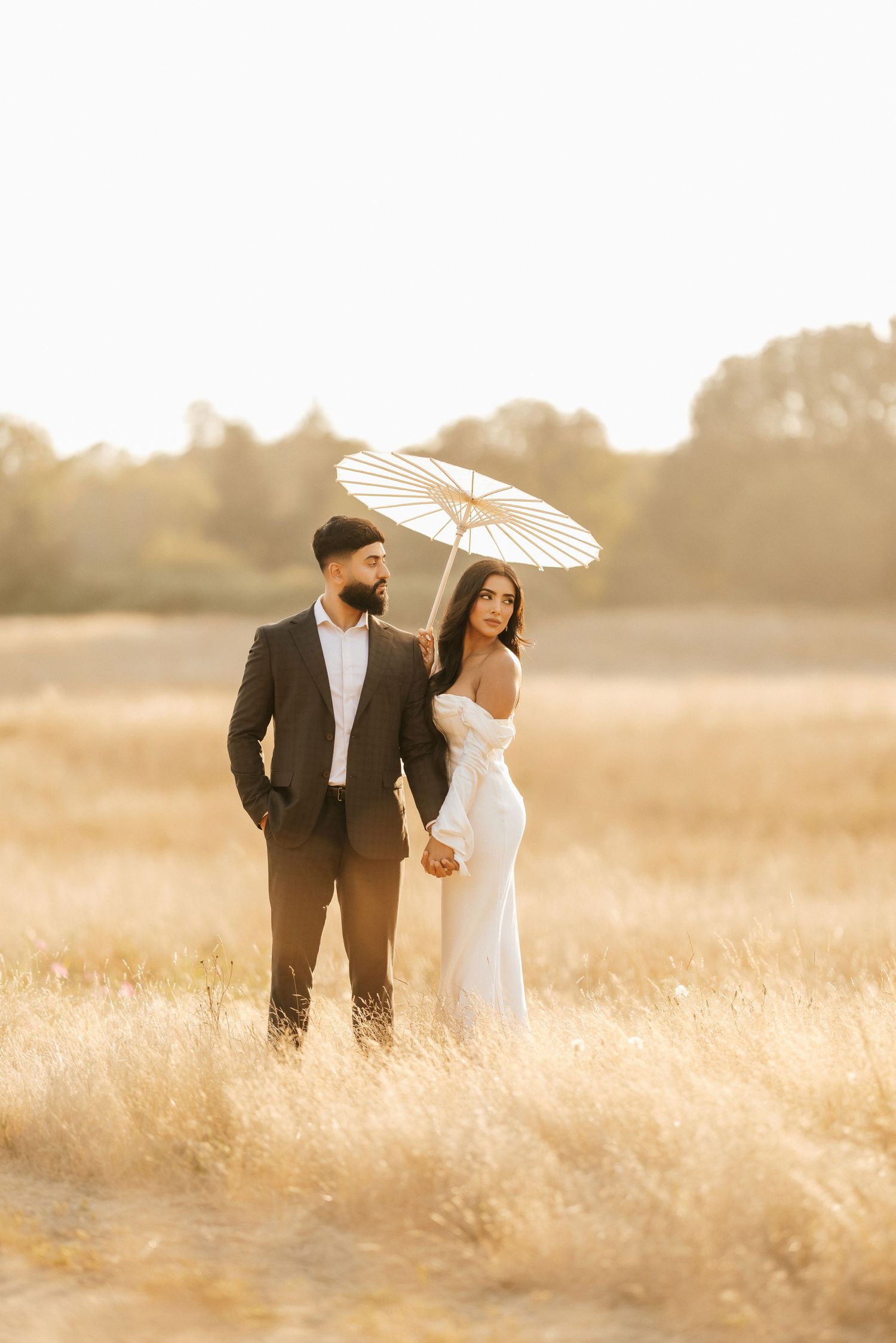 Dancing couple laughs together near vintage car during casual photo shoot.