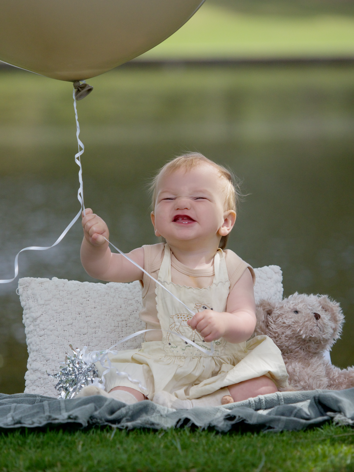 outdoor photo of a boys first birthday pulling a funny face hoding a big balloon