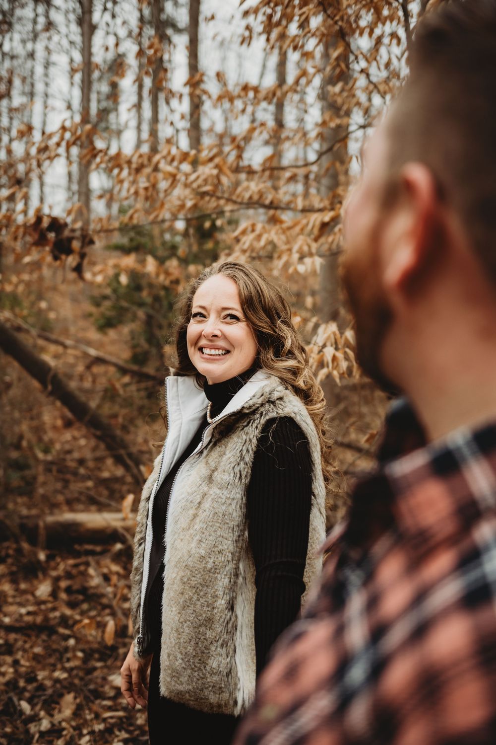 Candid autumn portrait captured during engagement photoshoot in a forest setting.
