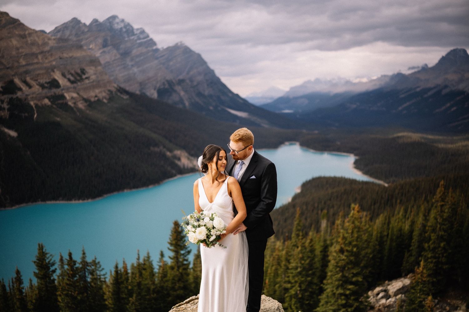 Bride and groom above the turquoise water of Peyto Lake near Lake Louise by a Banff wedding photographer