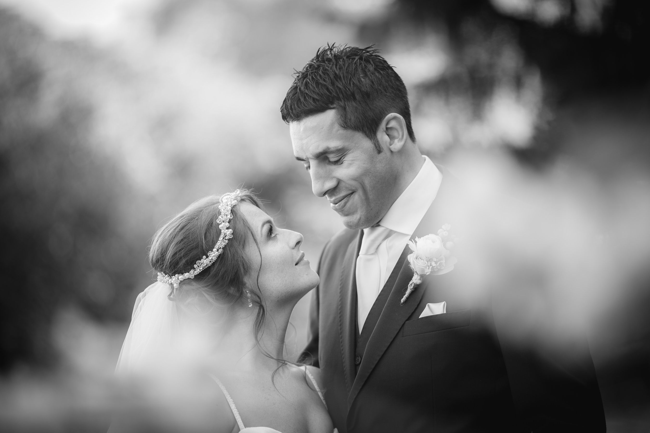 A romantic black and white wedding portrait shows a tender moment between newlyweds in soft focus.