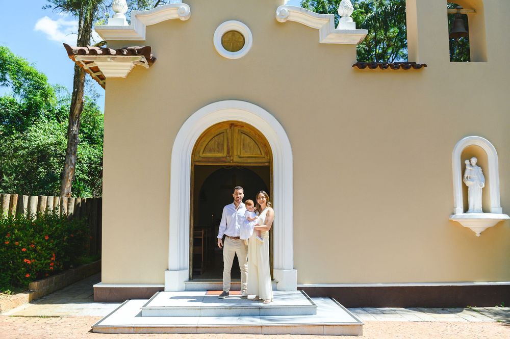 Couple posing at entrance of charming yellow Spanish-style chapel with arched doorway and statue niche.