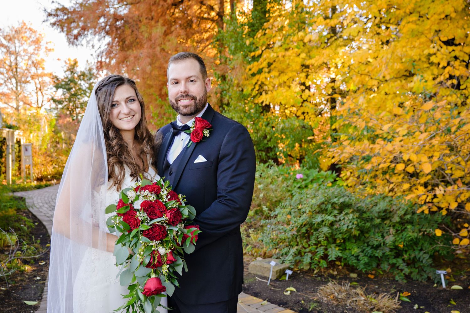 Bride and Groom posing in front of autumnal foliage at Fellows Riverside Gardens in Youngstown Ohio after their wedding ceremony in October.