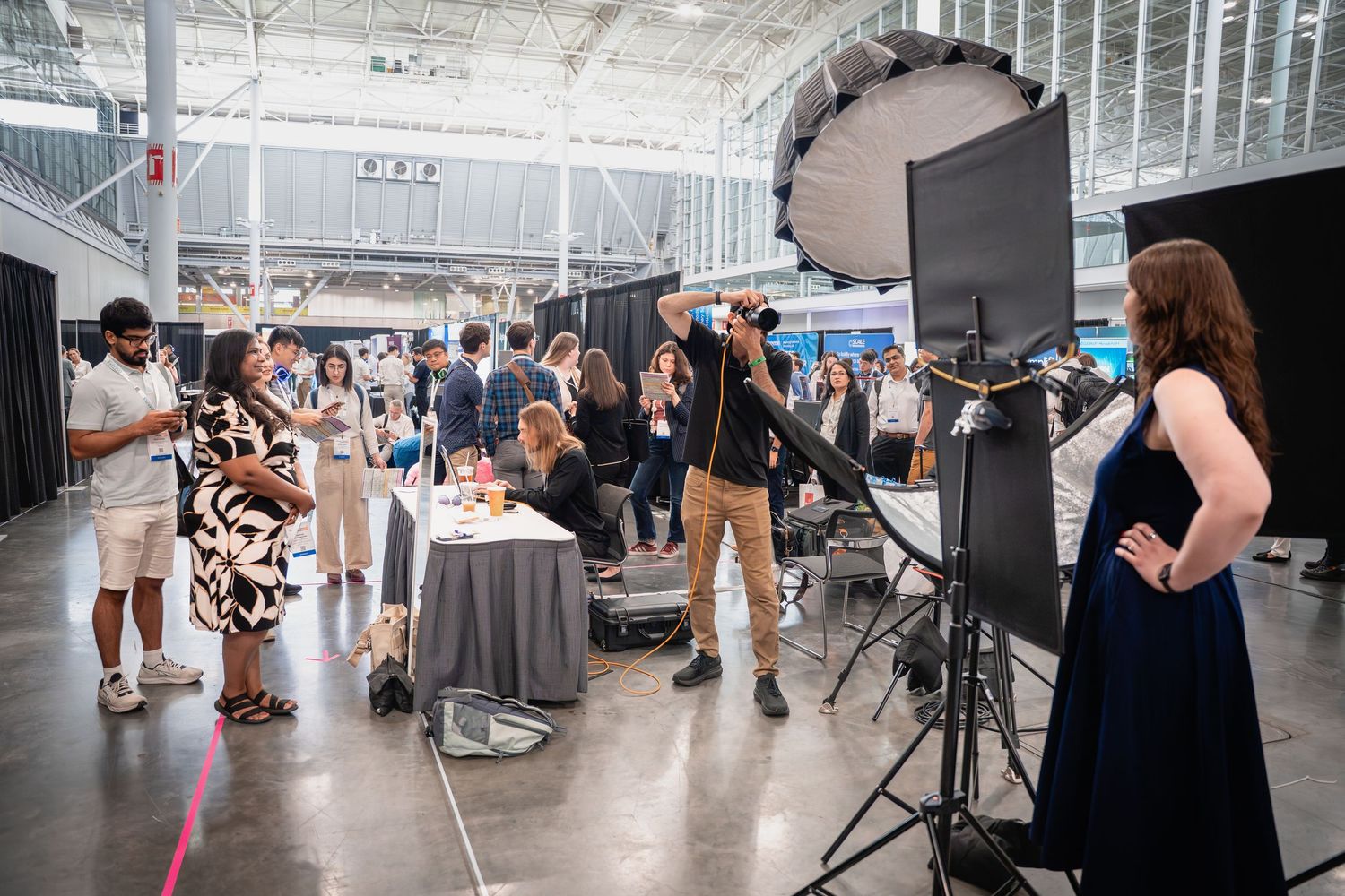Professional photo shoot setup at a convention center with lighting equipment, photographer, and attendees in formal attire.