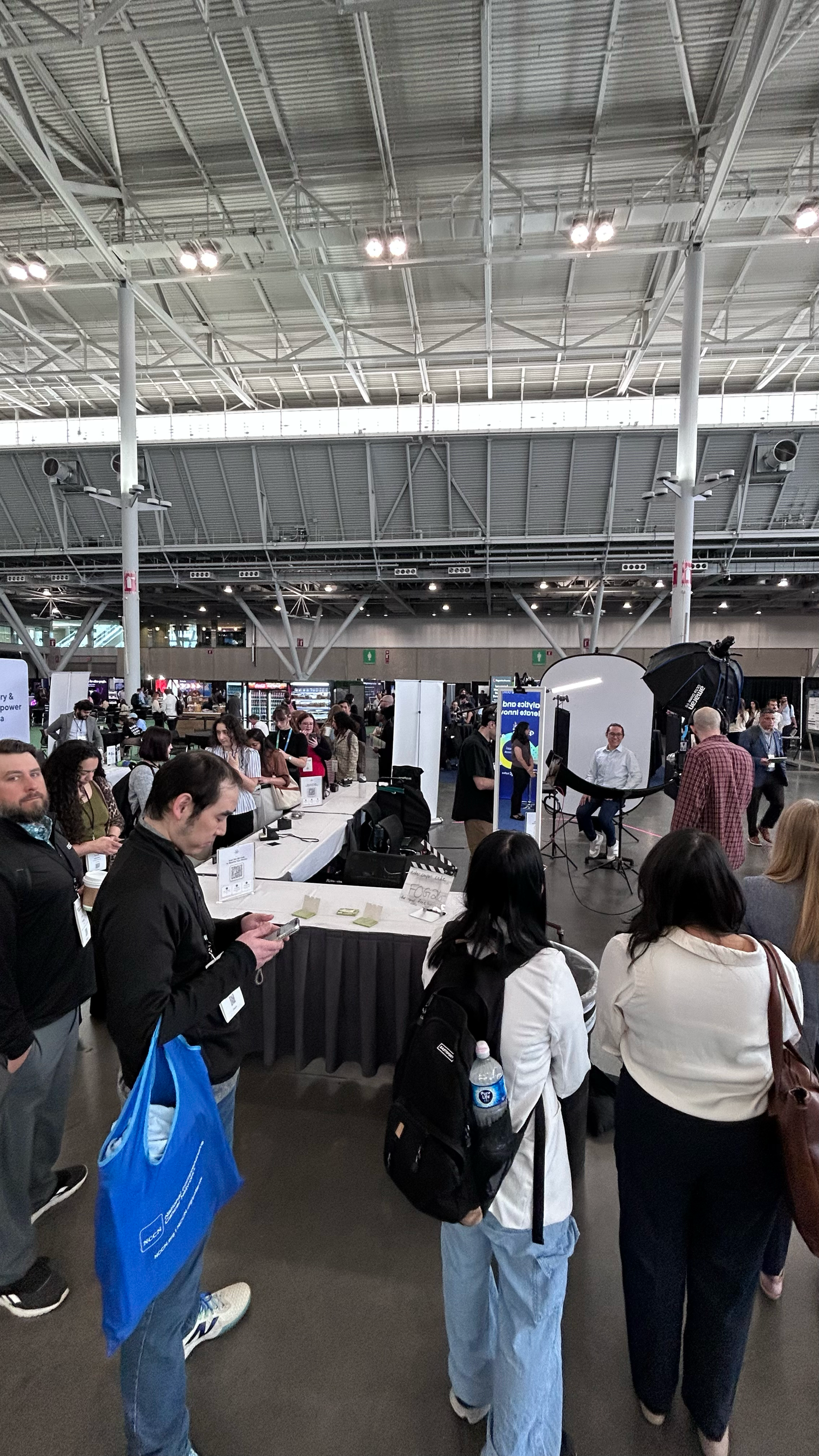 Busy indoor trade show or job fair event with attendees browsing vendor booths in a large convention center.