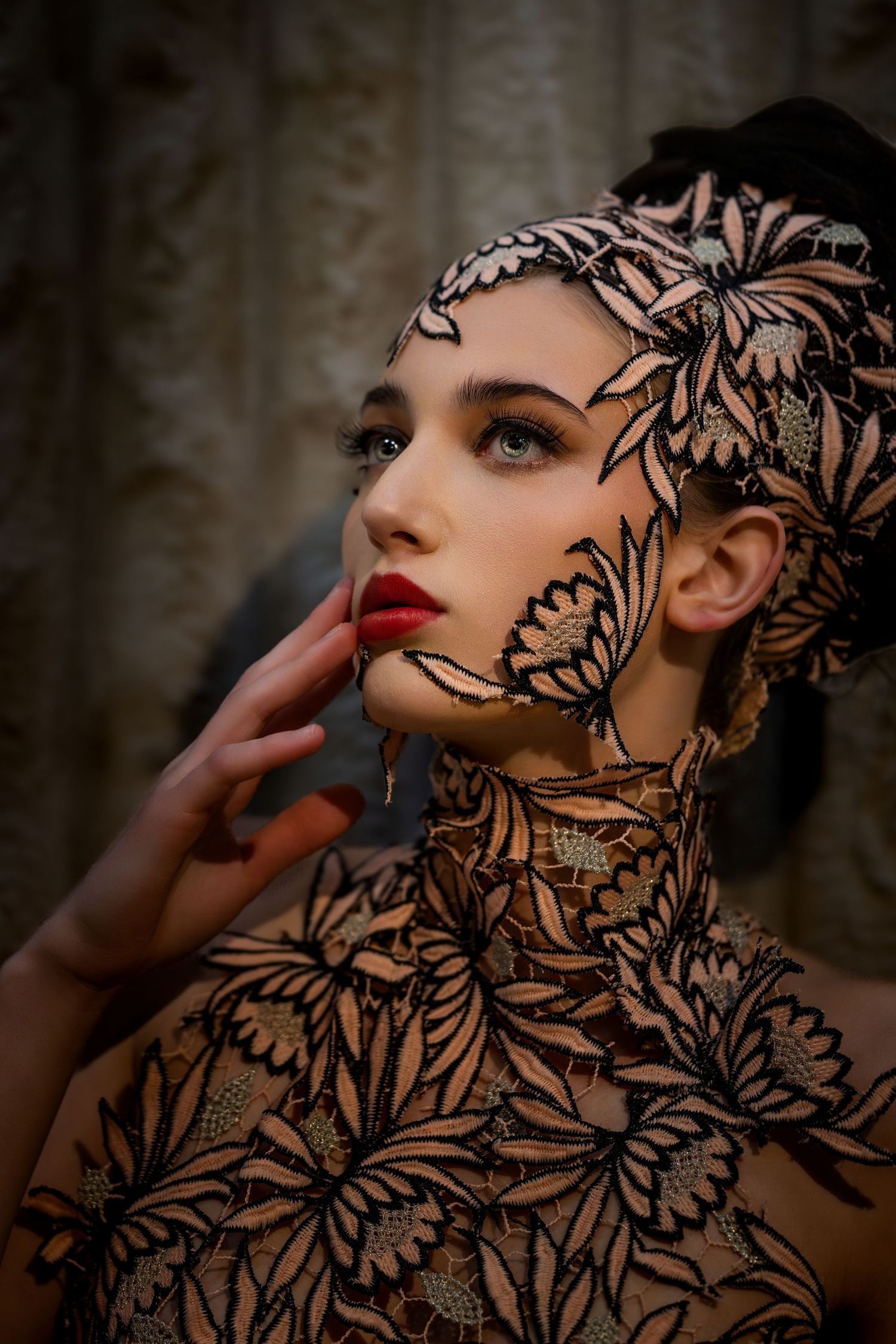 Artistic portrait of woman in intricate floral lace bodysuit and headpiece with red lips.