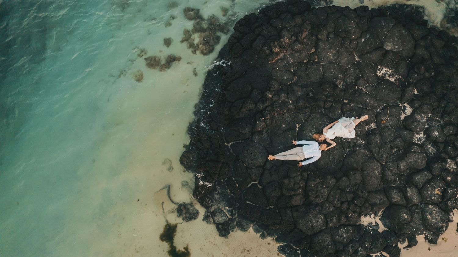 ouple lying on volcanic rocks photographed from above during a Mauritius wedding portrait session, Luminair Studio wedding photographer