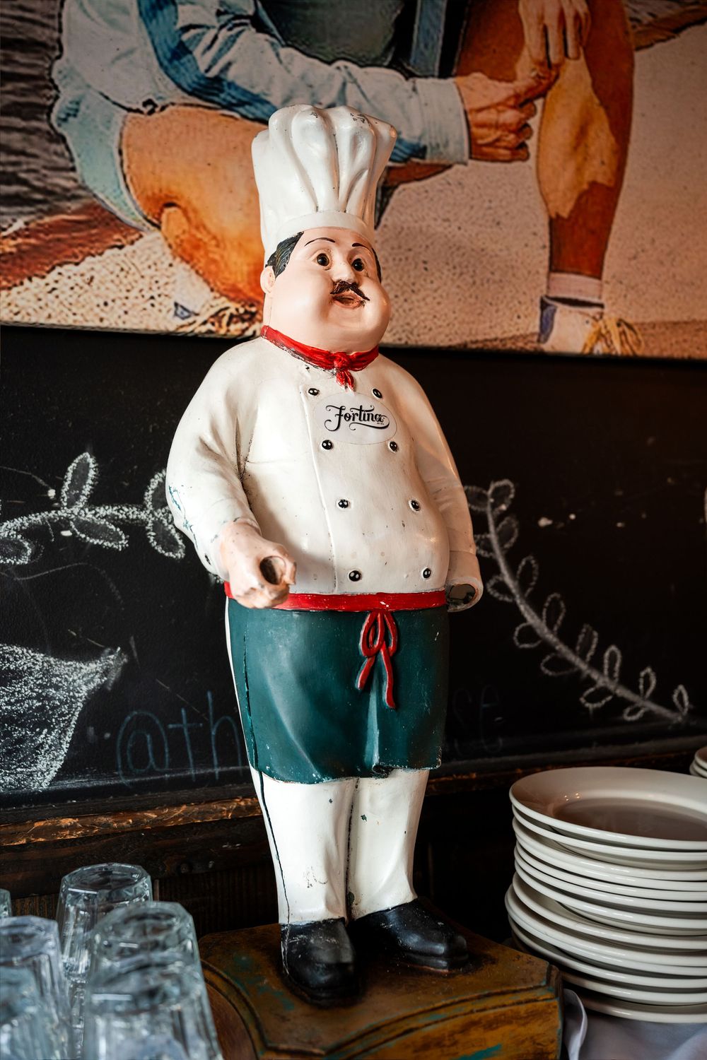 Decorative chef figurine statue wearing white uniform and toque hat displayed in a restaurant setting.