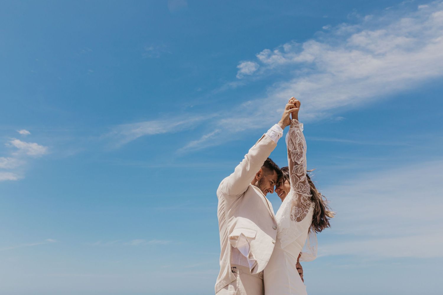 Bride and groom celebrating beneath the blue Byron Bay sky after their beach wedding, captured by a Byron Bay wedding photographer.
