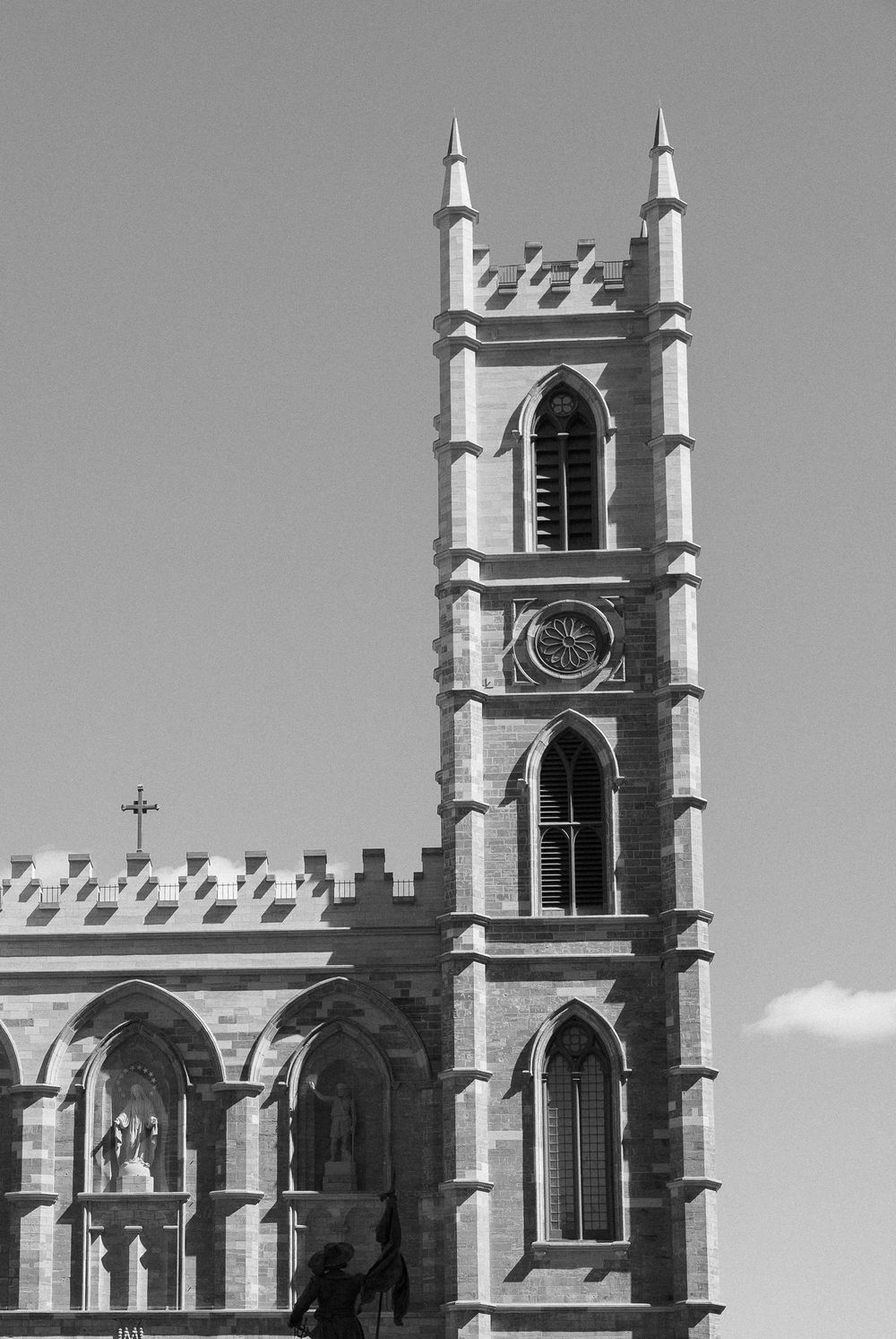 Black and white photo of Notre-Dame Basilica tower in Montreal, featuring Gothic architecture, arched windows, and ornate stone detailing.