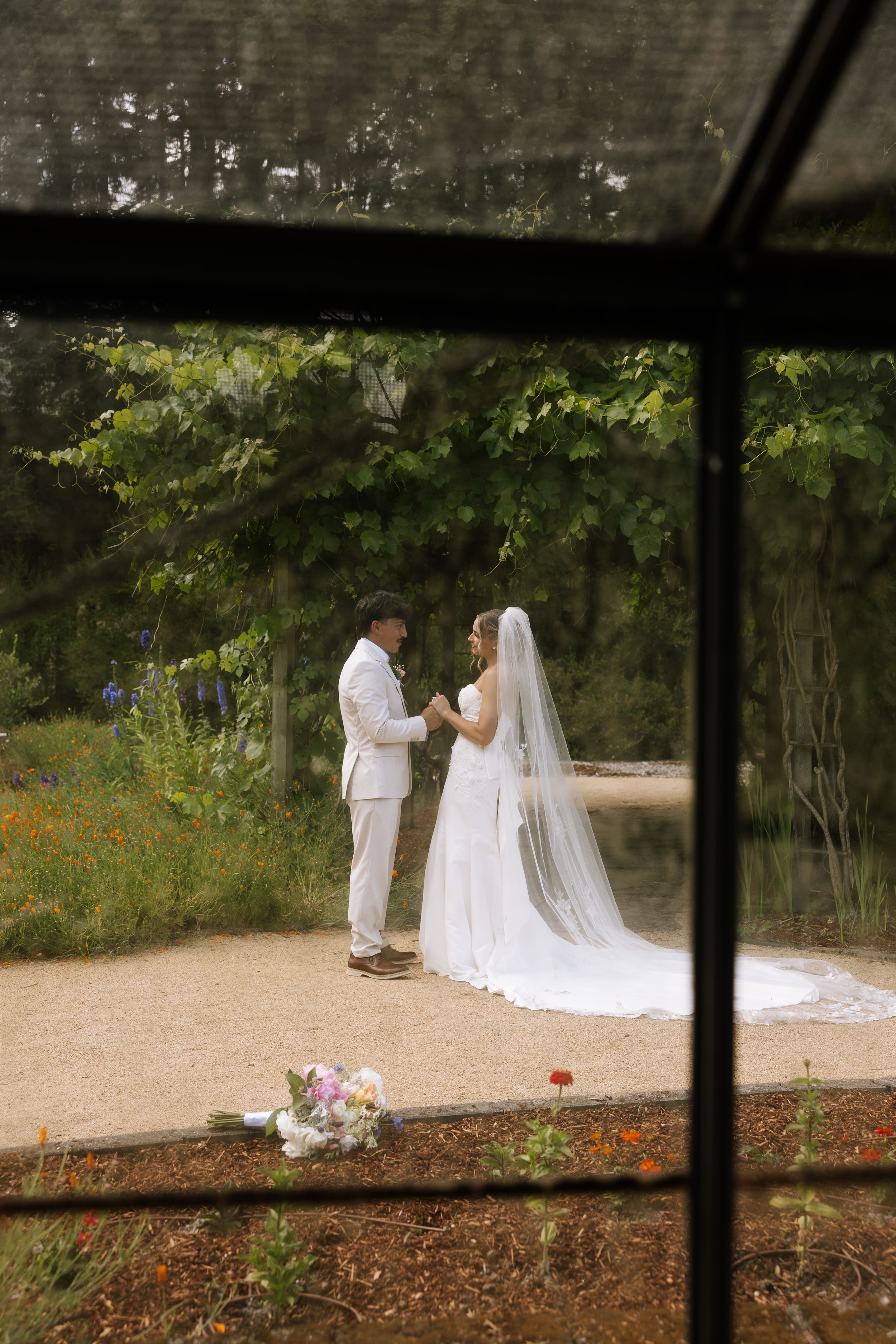 Bride and groom exchange vows in a lush garden ceremony, bride wearing a long white gown and veil.