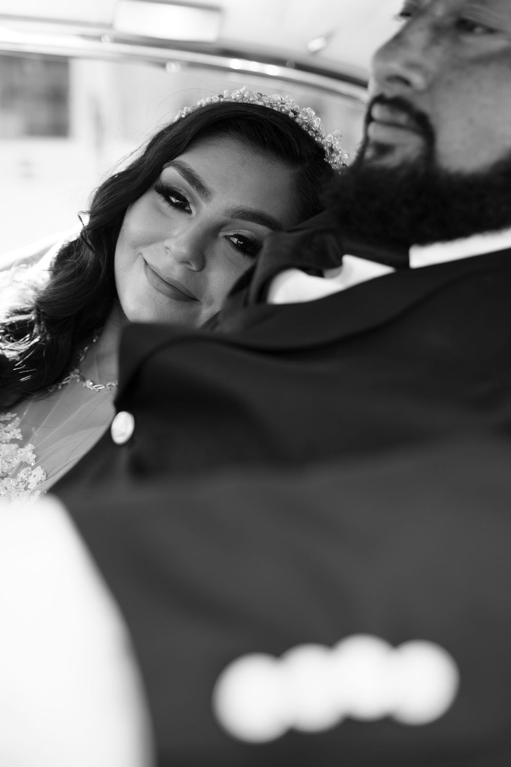Black and white wedding photo of a smiling bride leaning on groom's shoulder inside an Audi car.