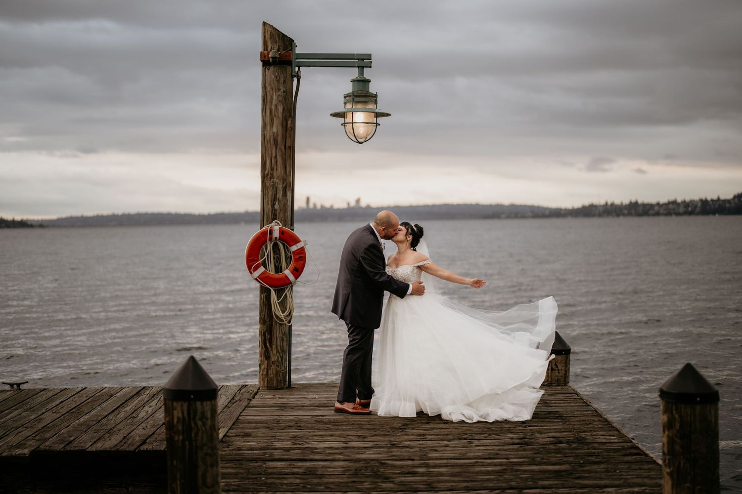Bride throwing dress on a dock in Tacoma, WA in their wedding attire.