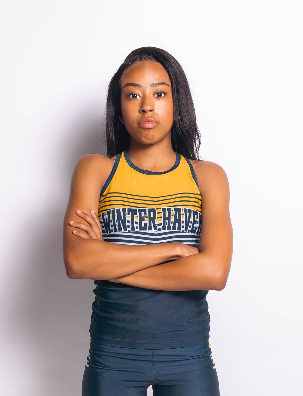 Young female athlete in Winter Haven sports top with arms crossed, posing confidently against white background.