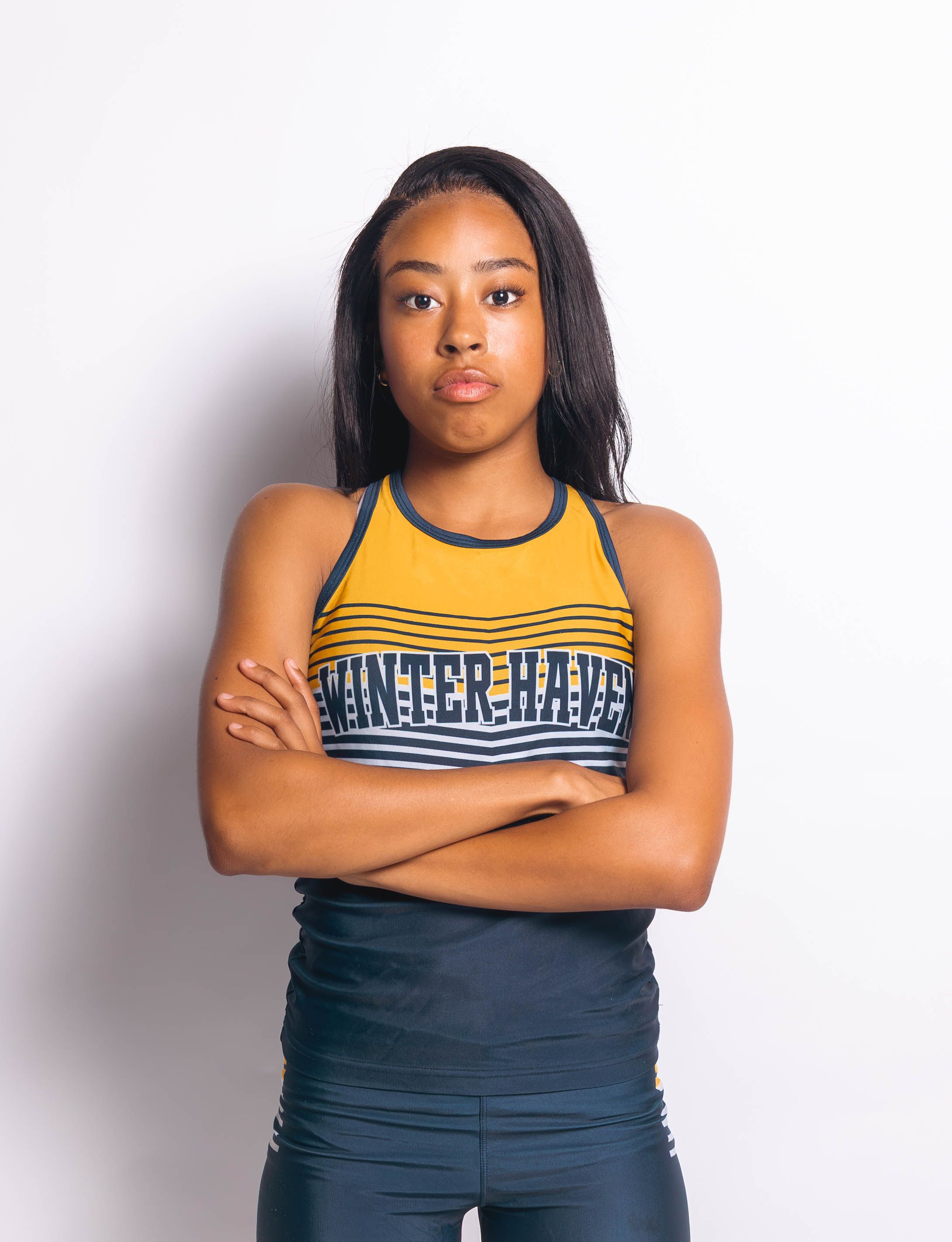 Young female athlete in Winter Haven sports top with arms crossed, posing confidently against white background.