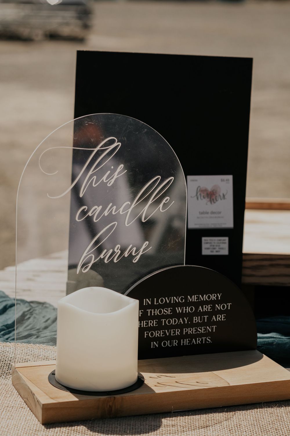 Wedding memorial candle display with acrylic sign reading 'This candle burns in loving memory' on wooden base.
