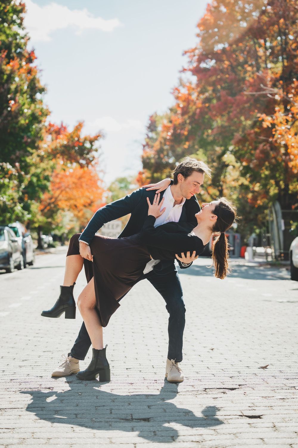 Couple dancing a romantic dip on a cobblestone street surrounded by colorful autumn trees on a sunny day in washington DC