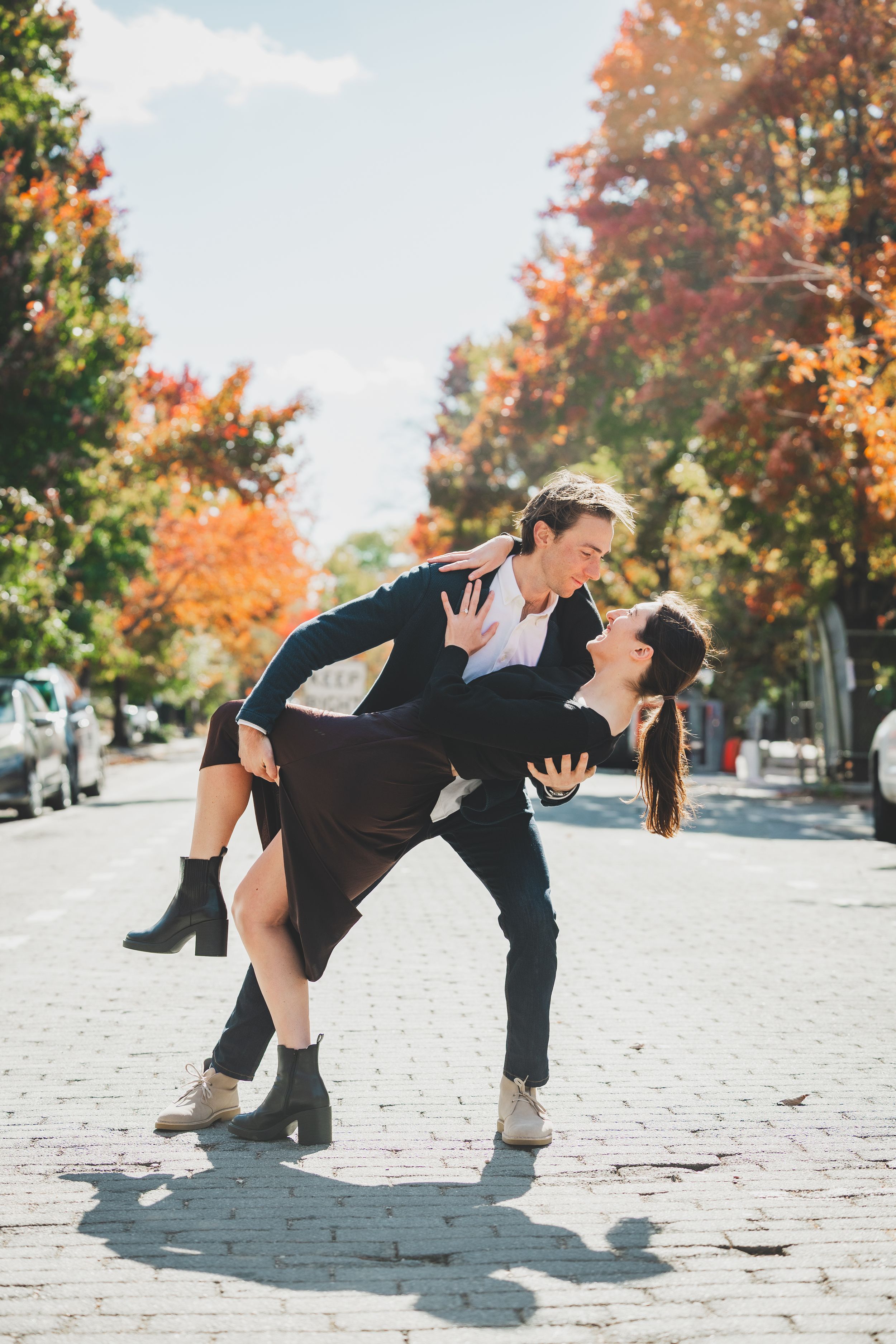 Couple dancing a romantic dip on a cobblestone street surrounded by colorful autumn trees on a sunny day in washington DC
