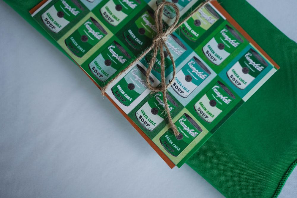 Green Campbell's Soup themed gift wrap tied with twine string on a green fabric background.