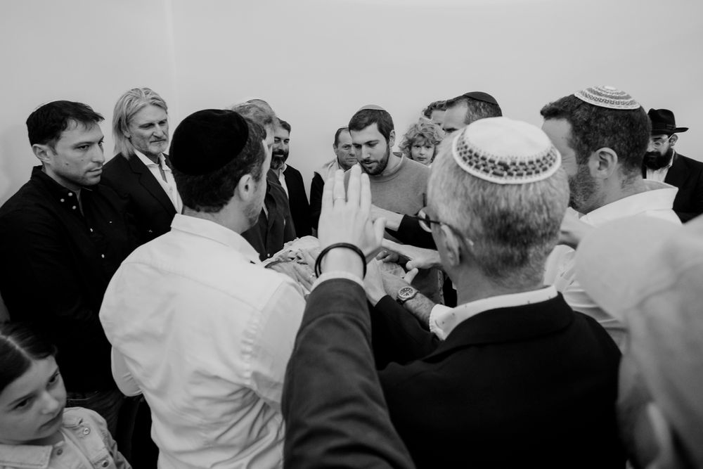 Black and white photo of a Jewish group gathering, men wearing kippot during a traditional religious ceremony.