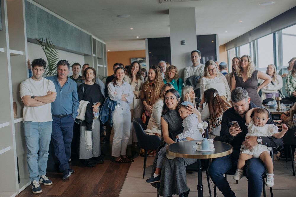 A large group of people gathered indoors at a modern venue, posing together for a photo at a social event.